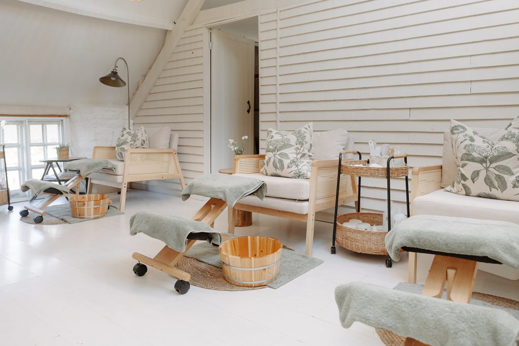 The Loft Beauty Therapy Room, a beauty therapy space with whitewashed panelled walls, pedicure stools and rattan chairs